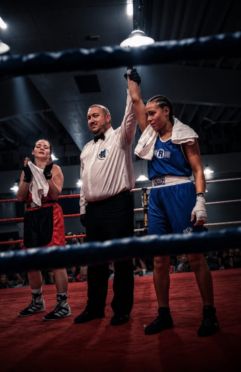 Arbitre levant le bras d'une boxeuse de TEAM KJA à l'annonce de sa victoire